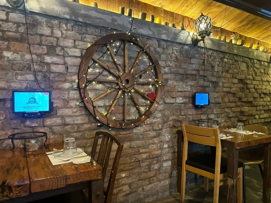 Wall with customer photos and seating at Hongdae Hwadeok Pizza