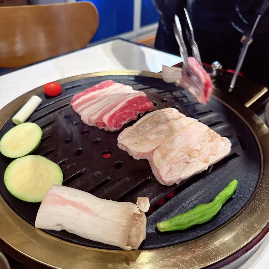 Staff grilling the Dwaeji Hangeun Set meat