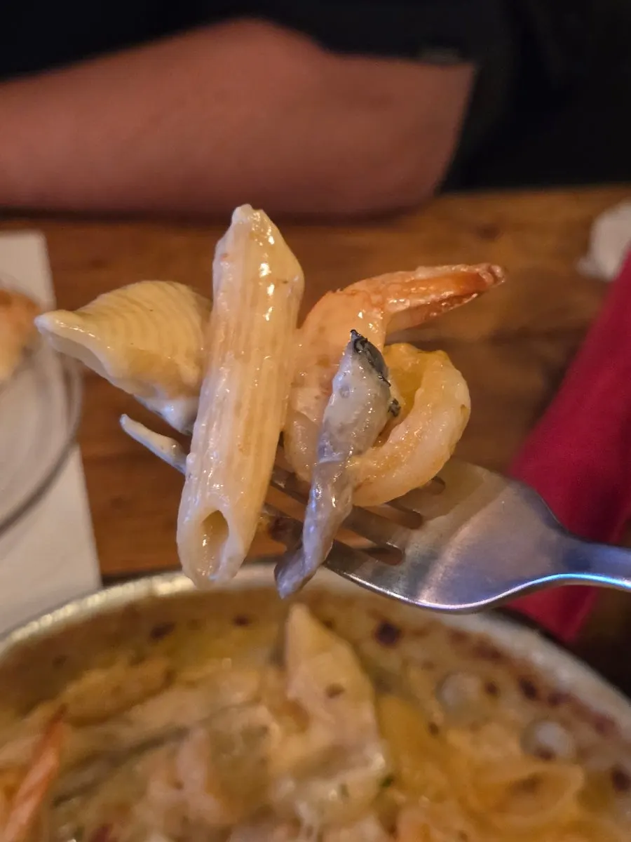 A bite of penne with stretchy melted cheese