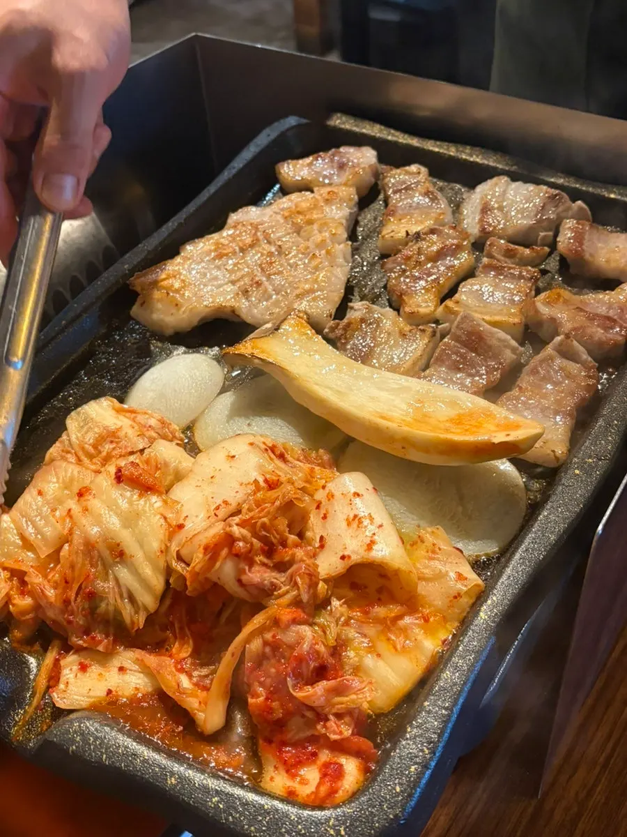 Pork belly and kimchi cooking on the grill