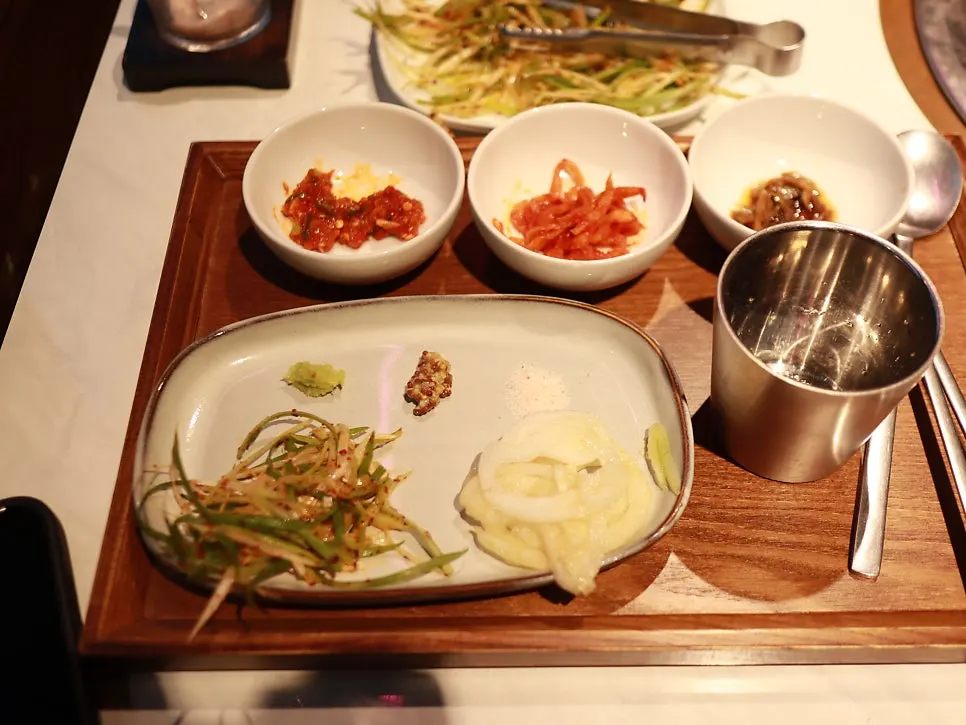 Side dish bowls including sliced green onion and pickled onion
