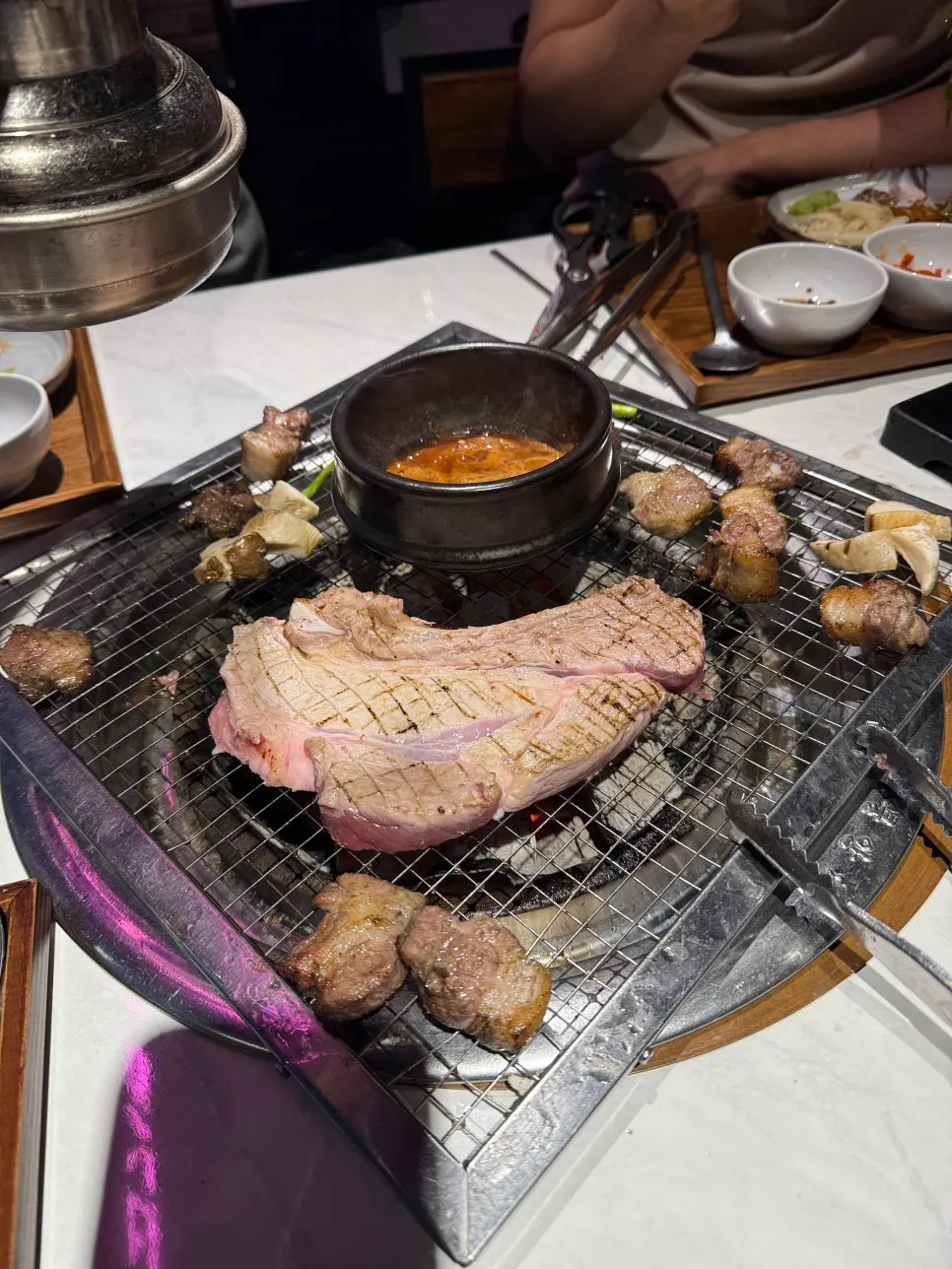 Stone pot of meljeot sauce warming on the side of the grill