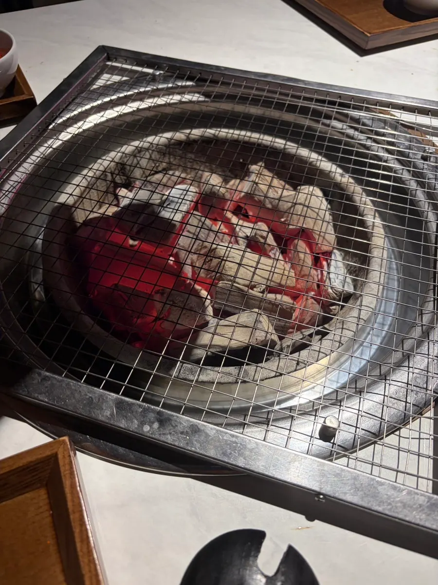 Pork belly grilling on the charcoal fire grate