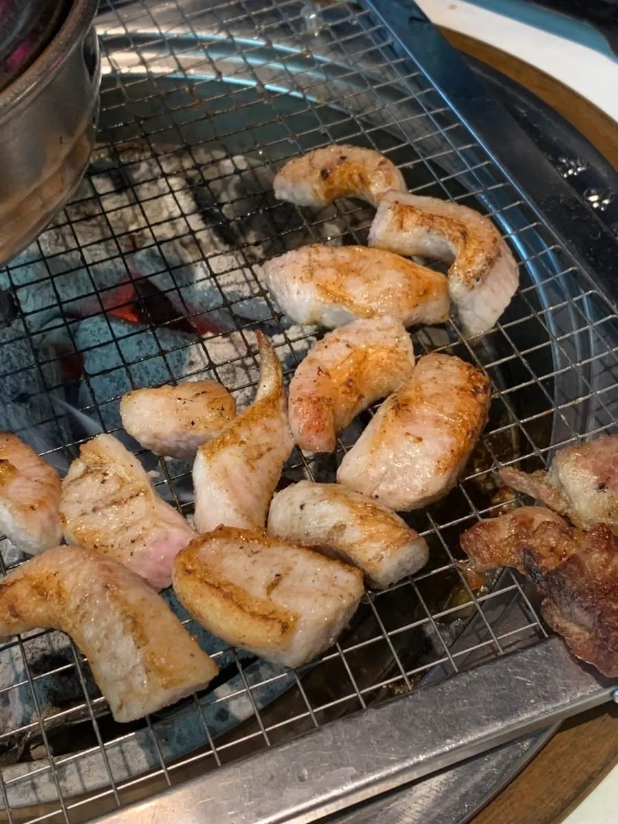 Pork jowl grilling over charcoal