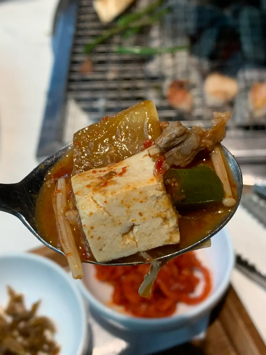 A spoonful of beef doenjang stew full of ingredients