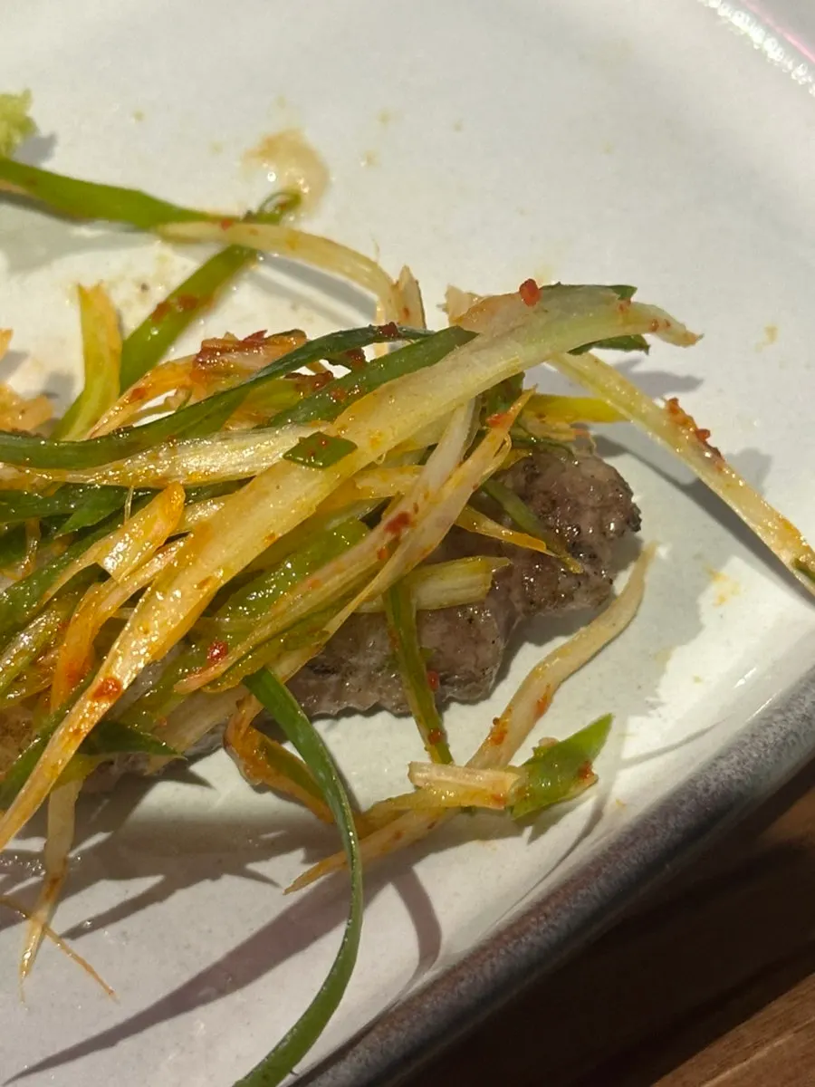 Doenjang stew served alongside a piece of grilled meat