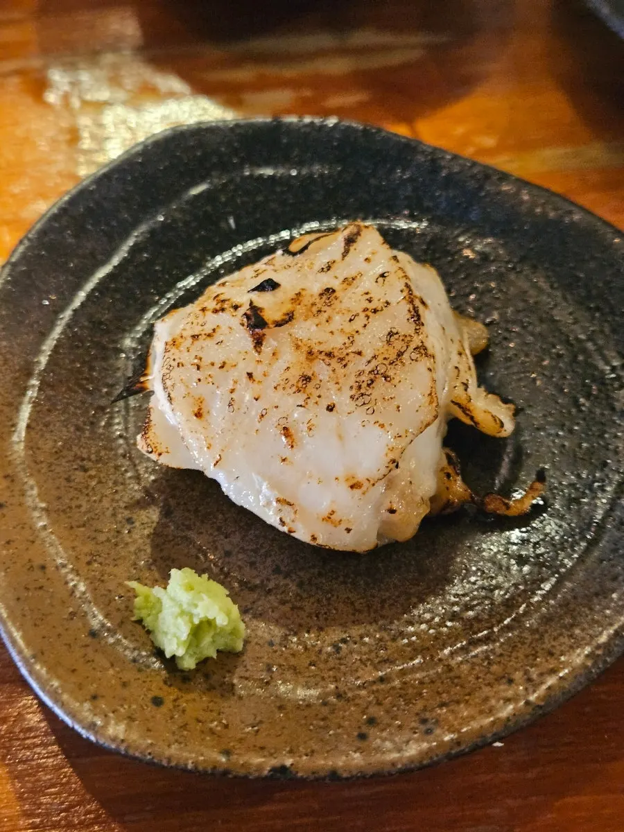 직원이 건네준 토치로 그을린 생선살 한 점
