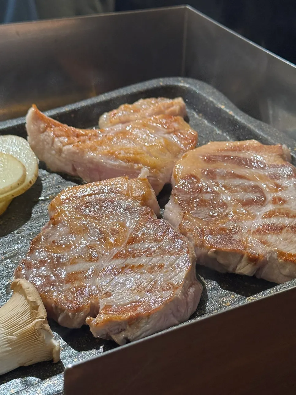 Pork neck and pork jowl grilling to a golden brown