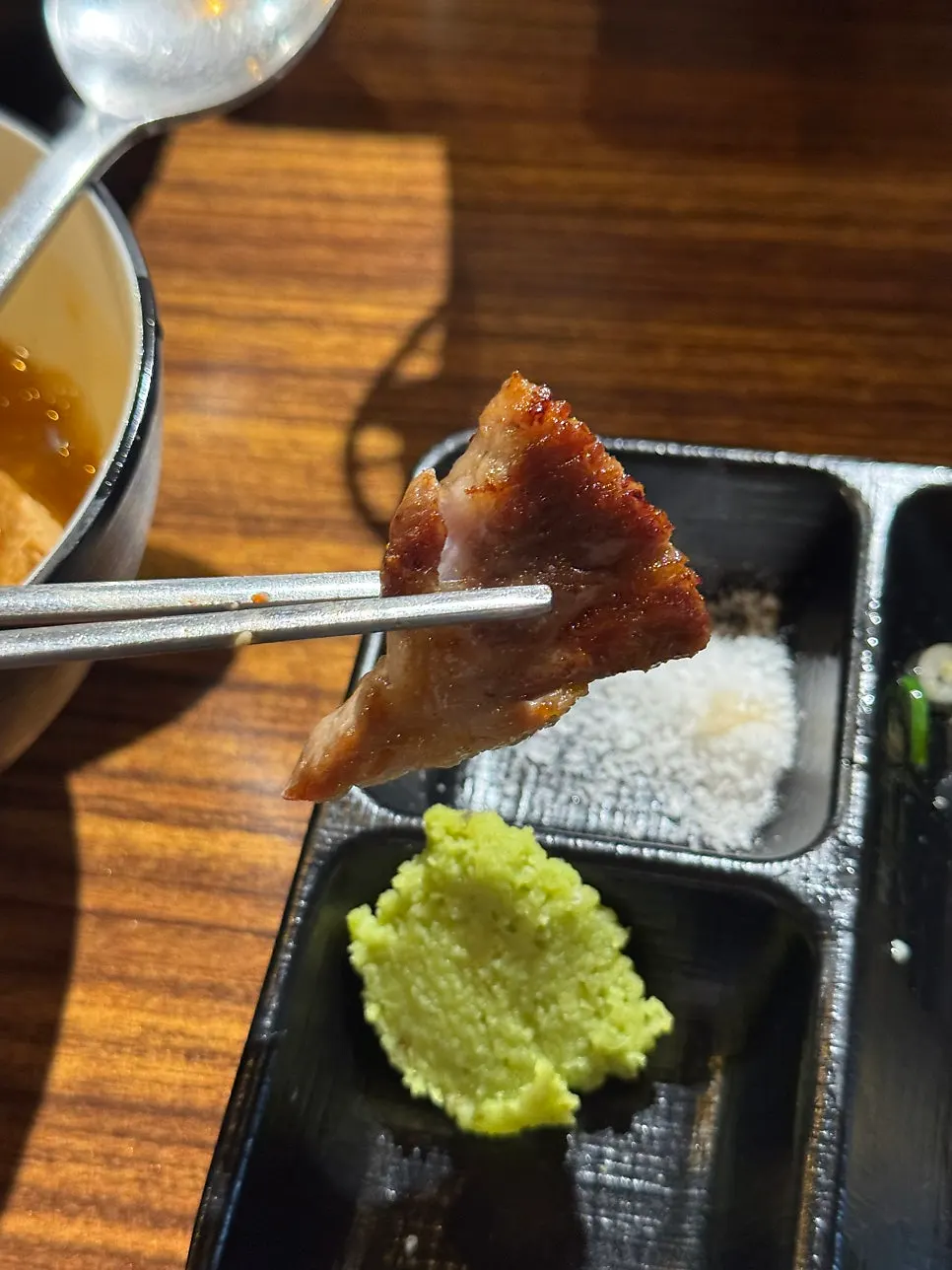 A piece of meat topped with salt and wasabi