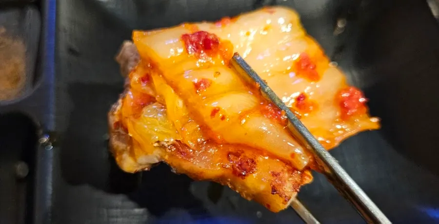 파절이를 올린 삼겹살 한 점