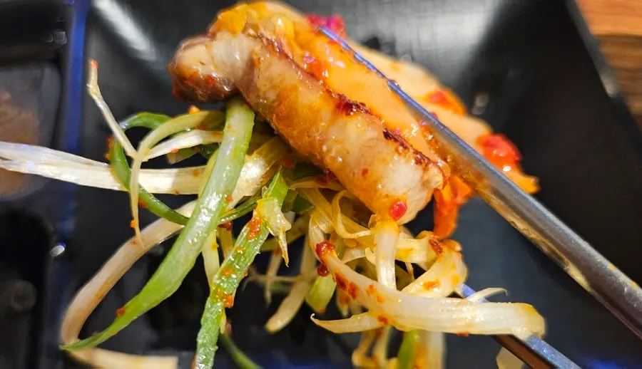 구운 김치를 올린 삼겹살 한 점