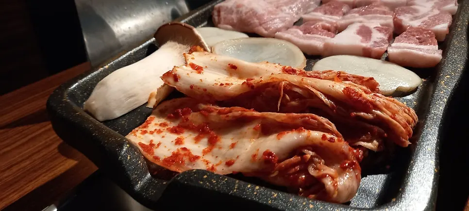 구운 김치를 올린 삼겹살 한입