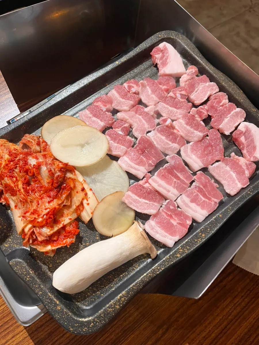 Kimchi and pork belly grilling together on the grate