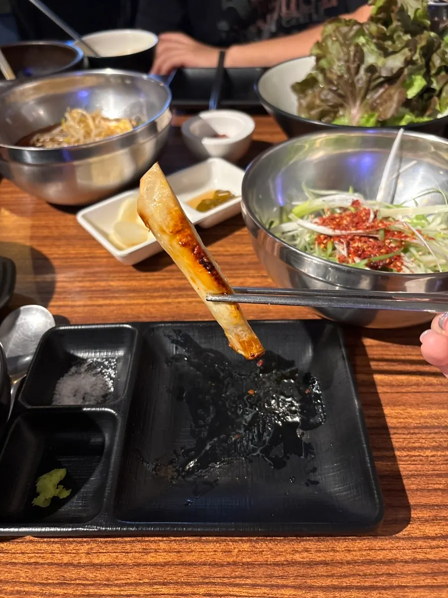 A piece of grilled meat with wasabi and salt on the side