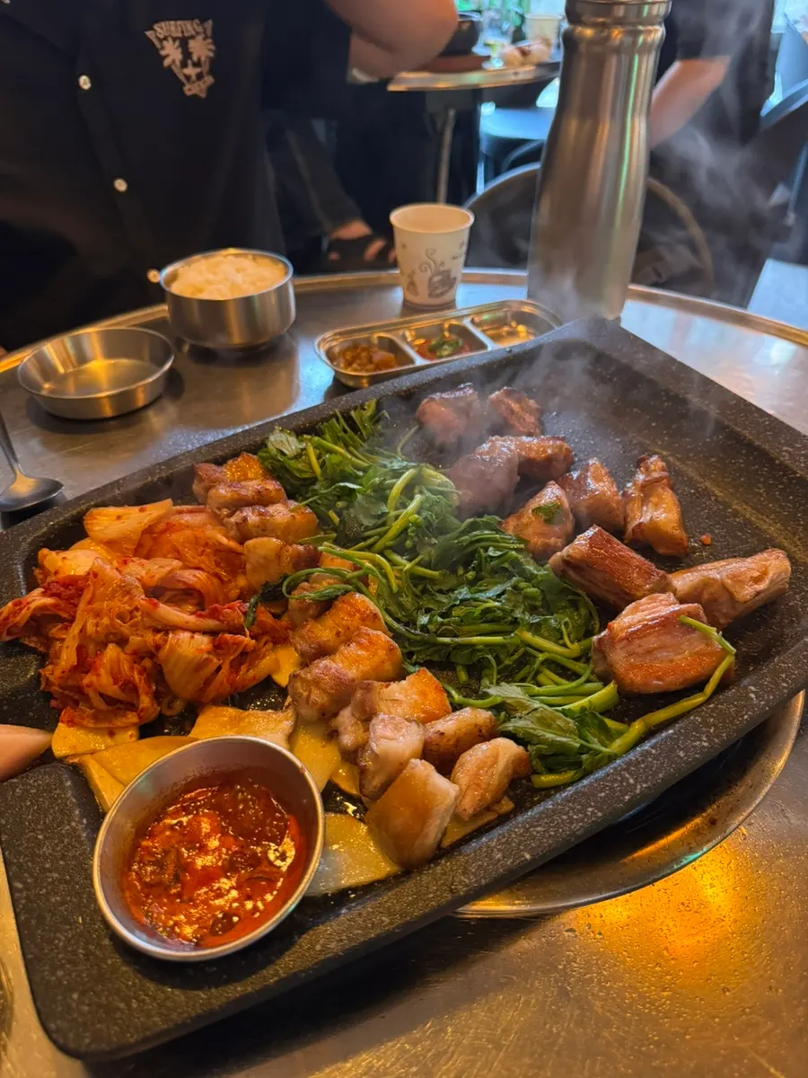 Potatoes, minari, and kimchi grilling alongside the meat