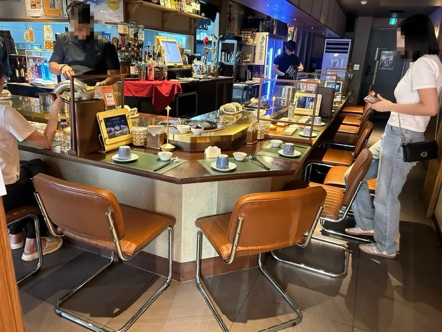 Interior view of Gukjeyangsik's open charcoal-grill counter seats