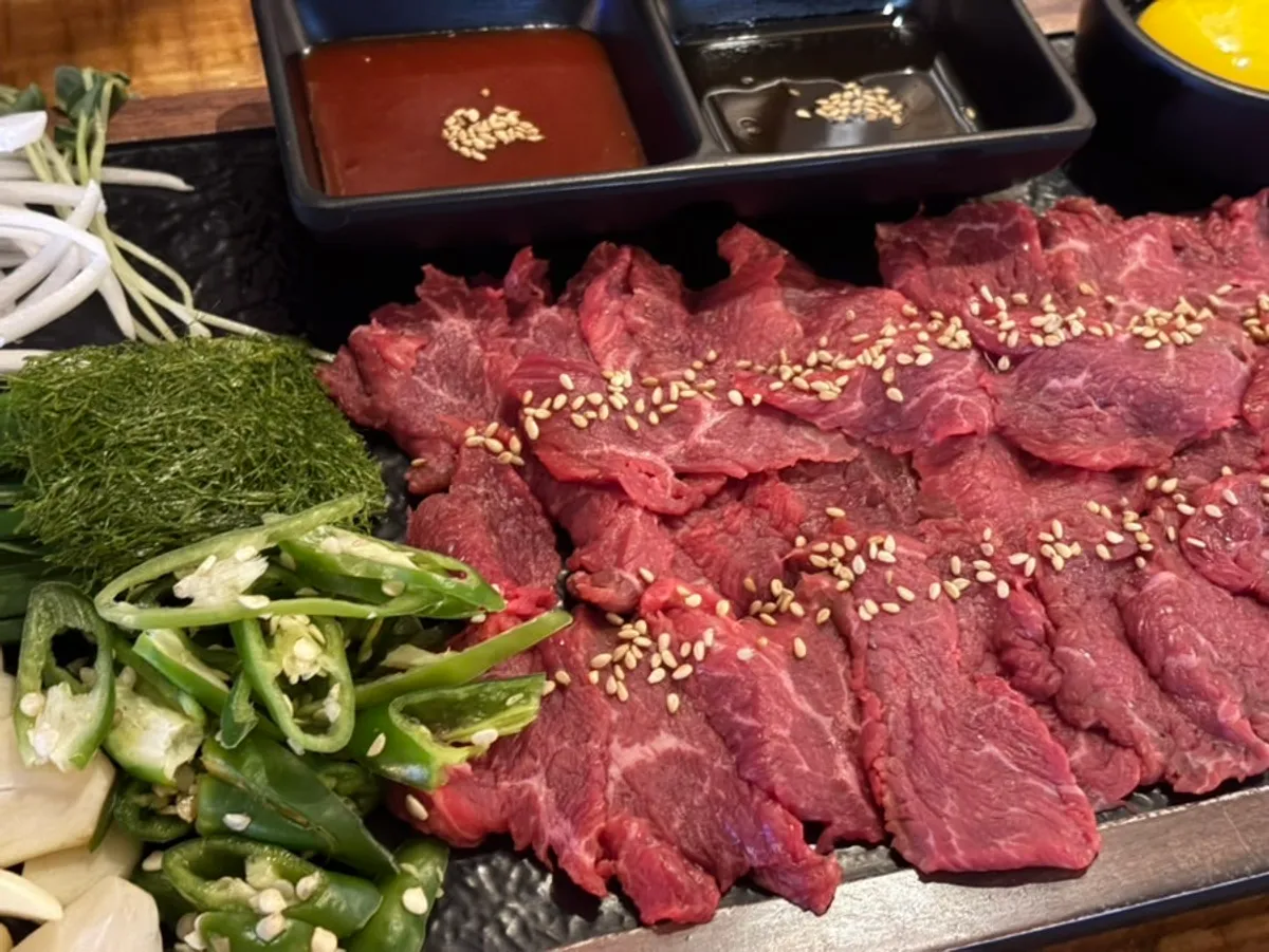 A plate of beef sashimi garnished with gamtae seaweed and egg yolk