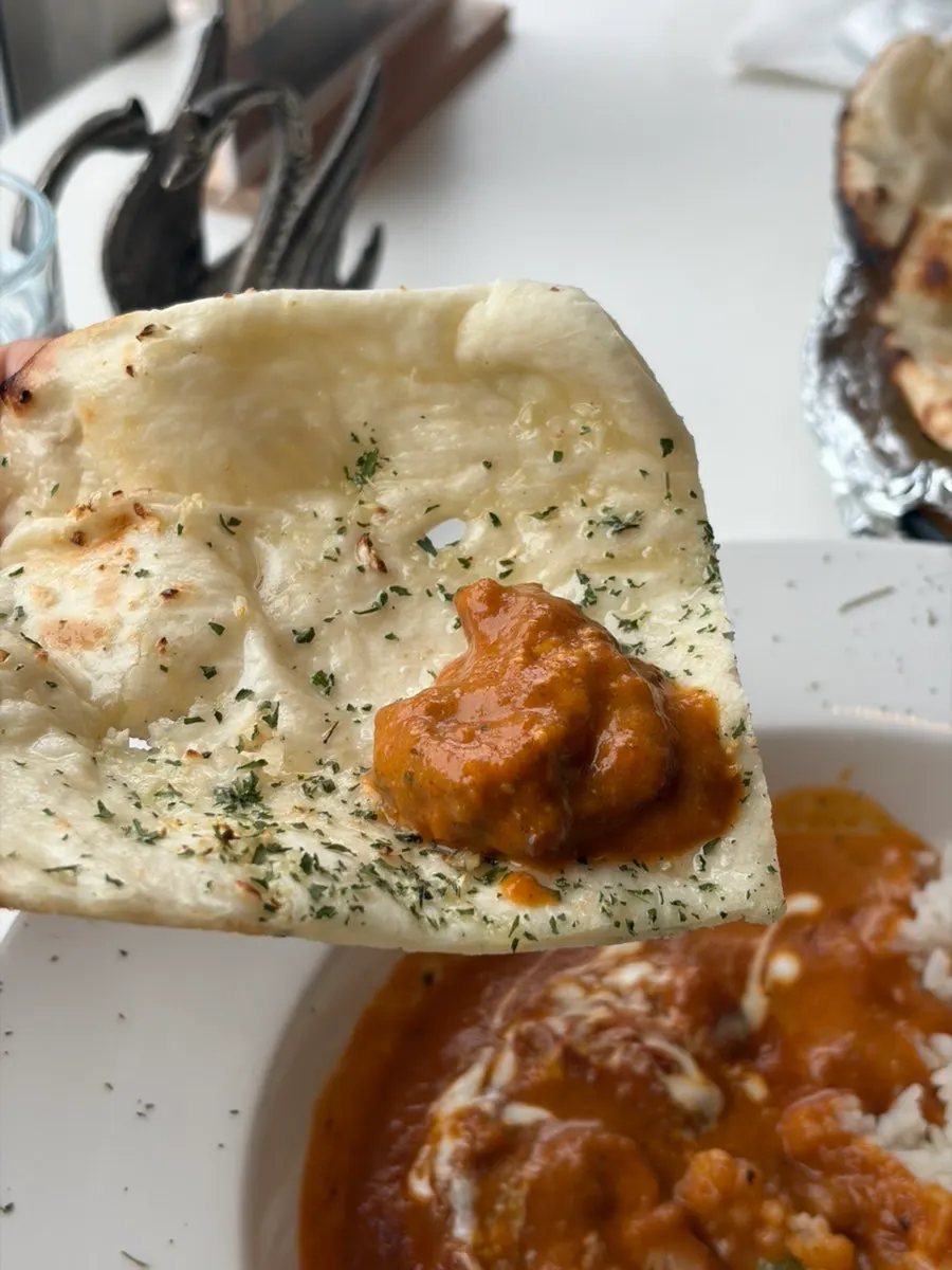 Tearing naan to dip into curry