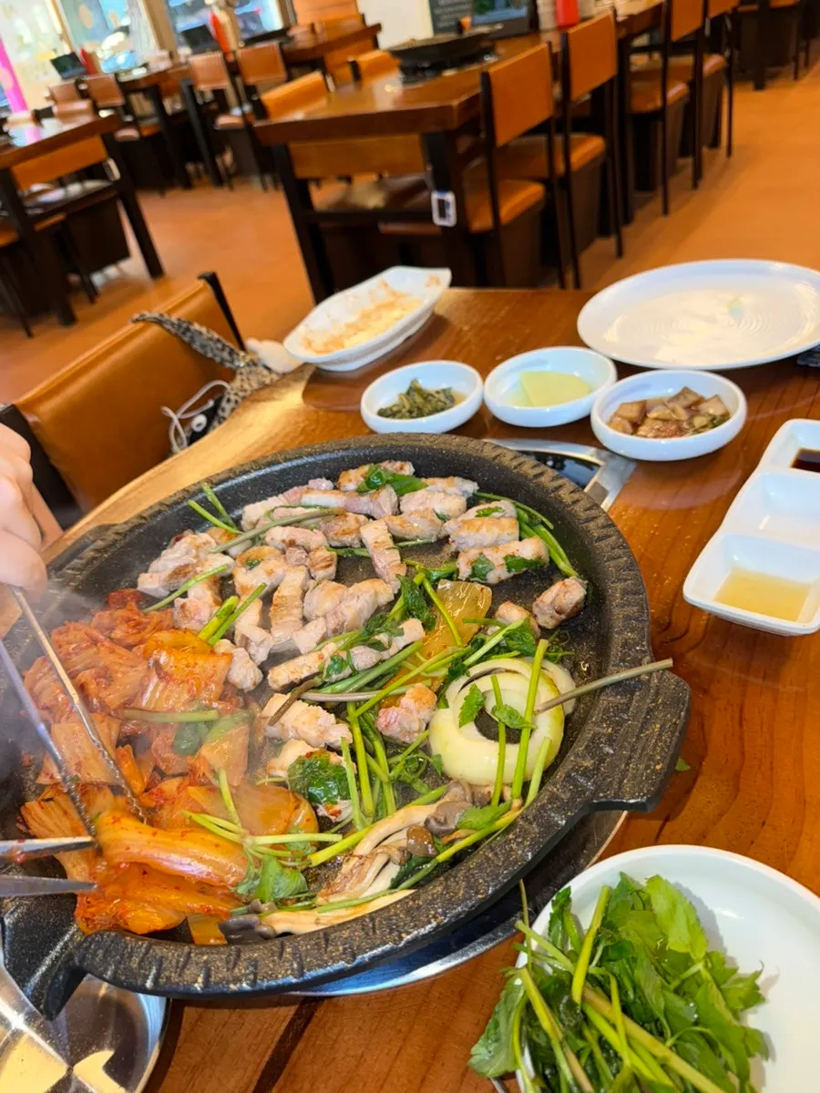불판에 올린 두툼한 삼겹살과 김치, 양파, 버섯