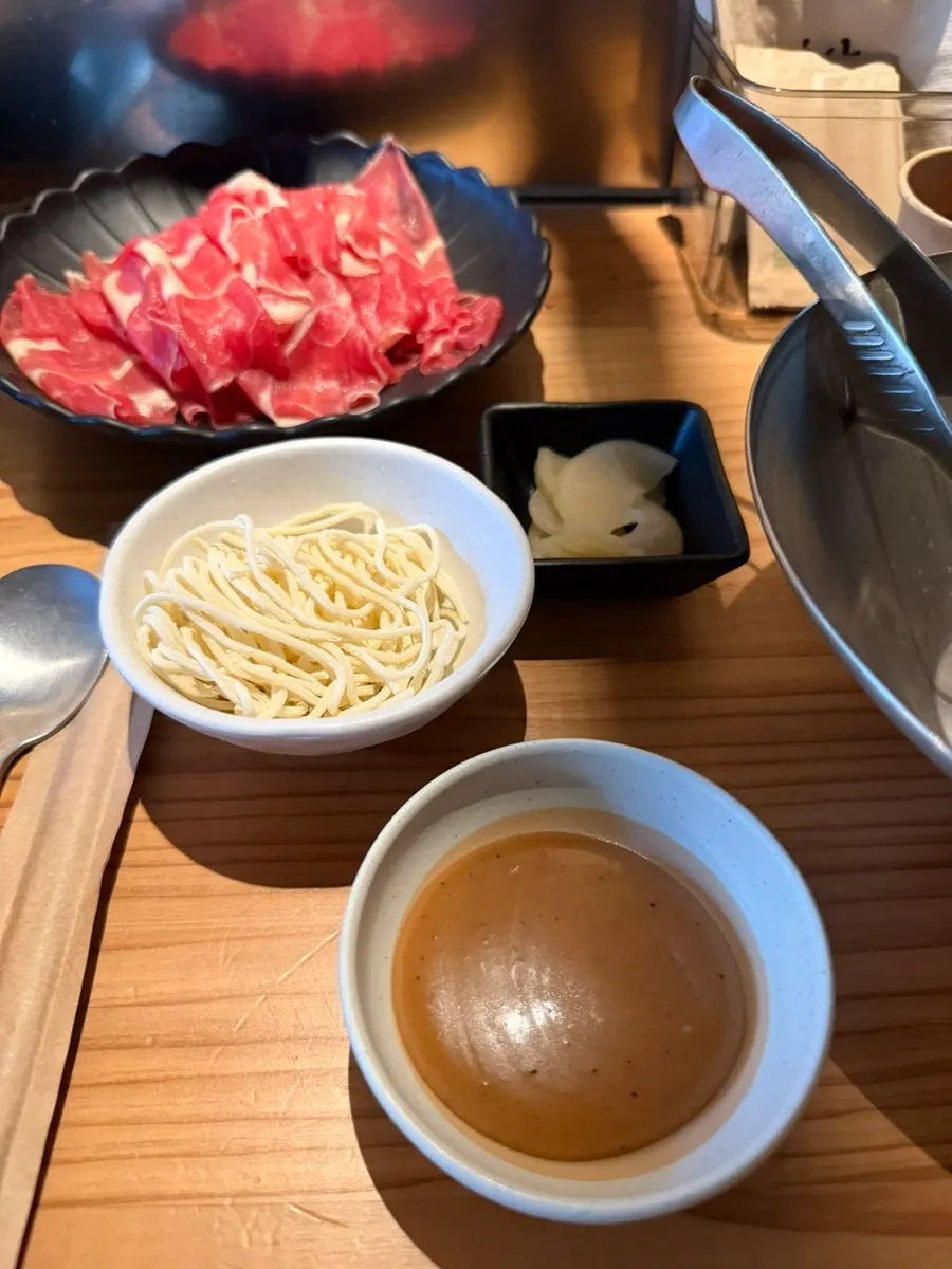 Clear broth shabu-shabu simmering with added ingredients