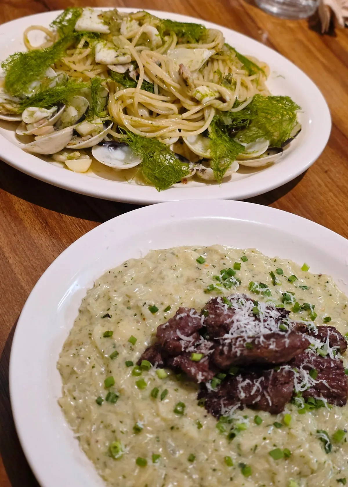 Gamtae vongole pasta and short rib basil risotto set on the table