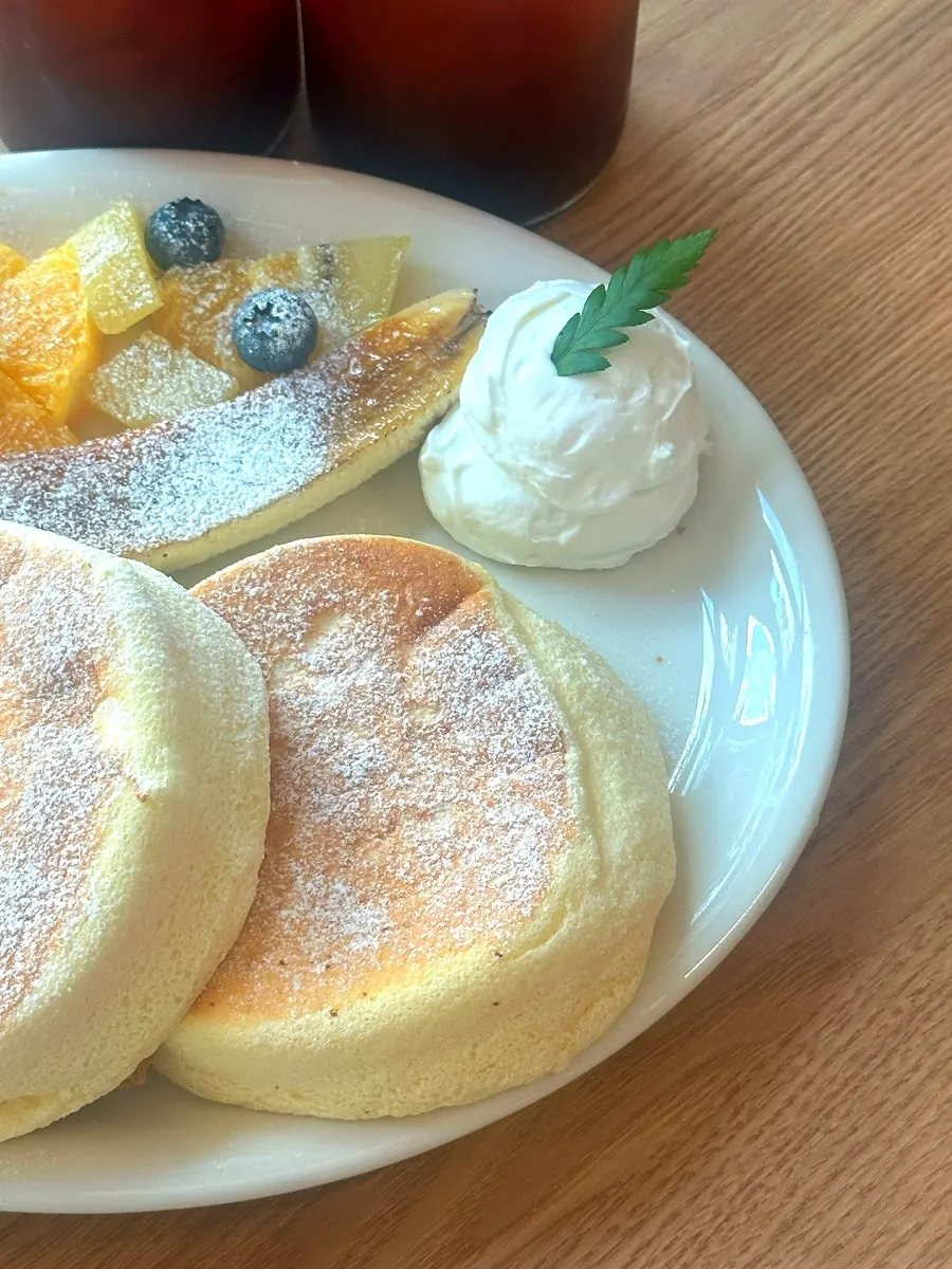 Two soufflé pancakes topped with whipped cream and fruit
