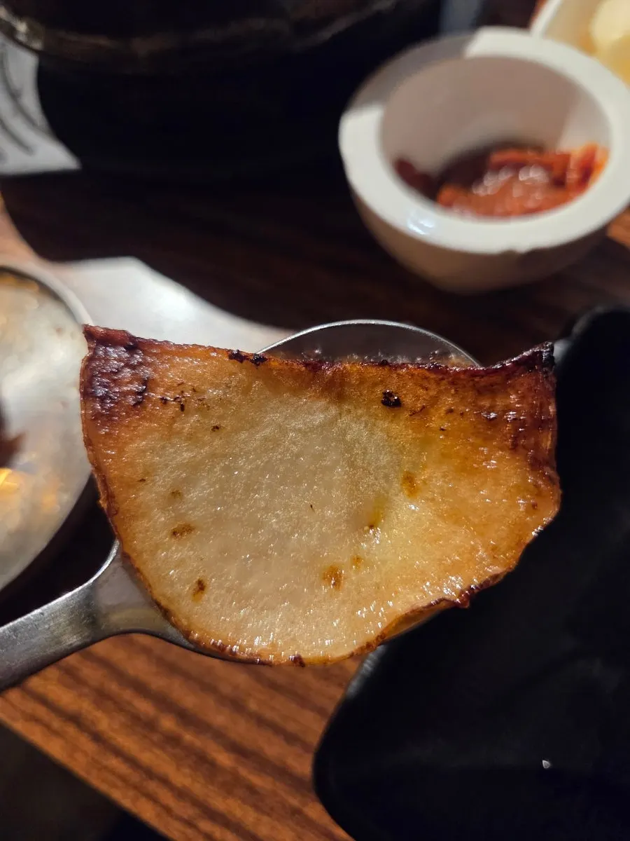 Thinly sliced potatoes grilled alongside the meat