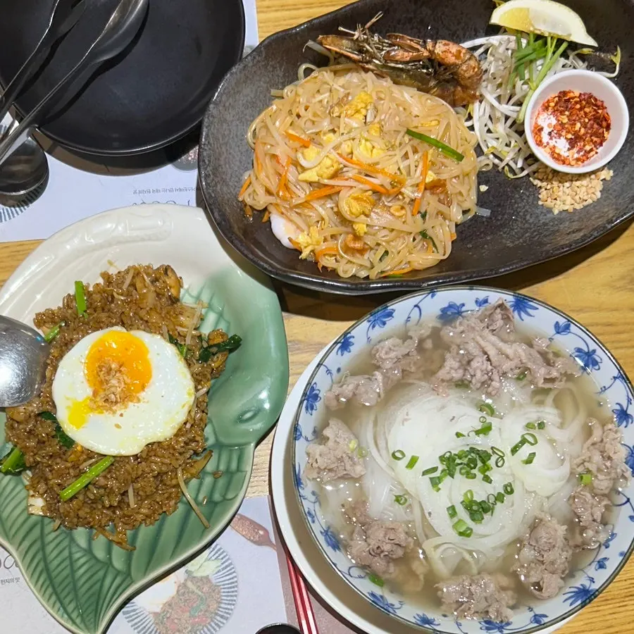 Table spread of giant prawn pad thai, pho, and nasi goreng