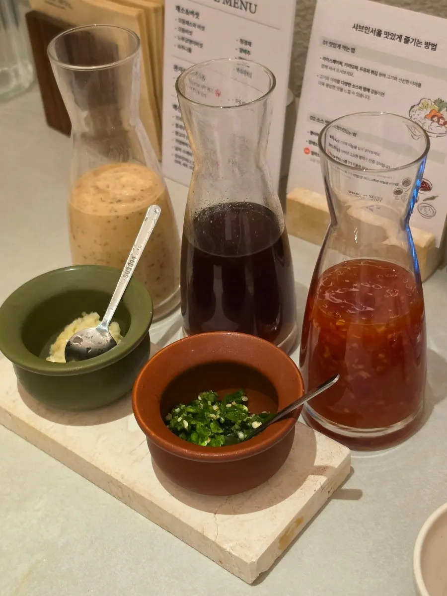 Three sauces — sesame, chili, soy — being prepared