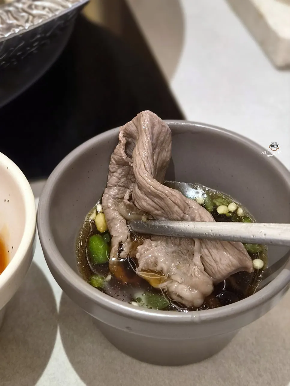 A piece of shabu-shabu meat dipped in sauce