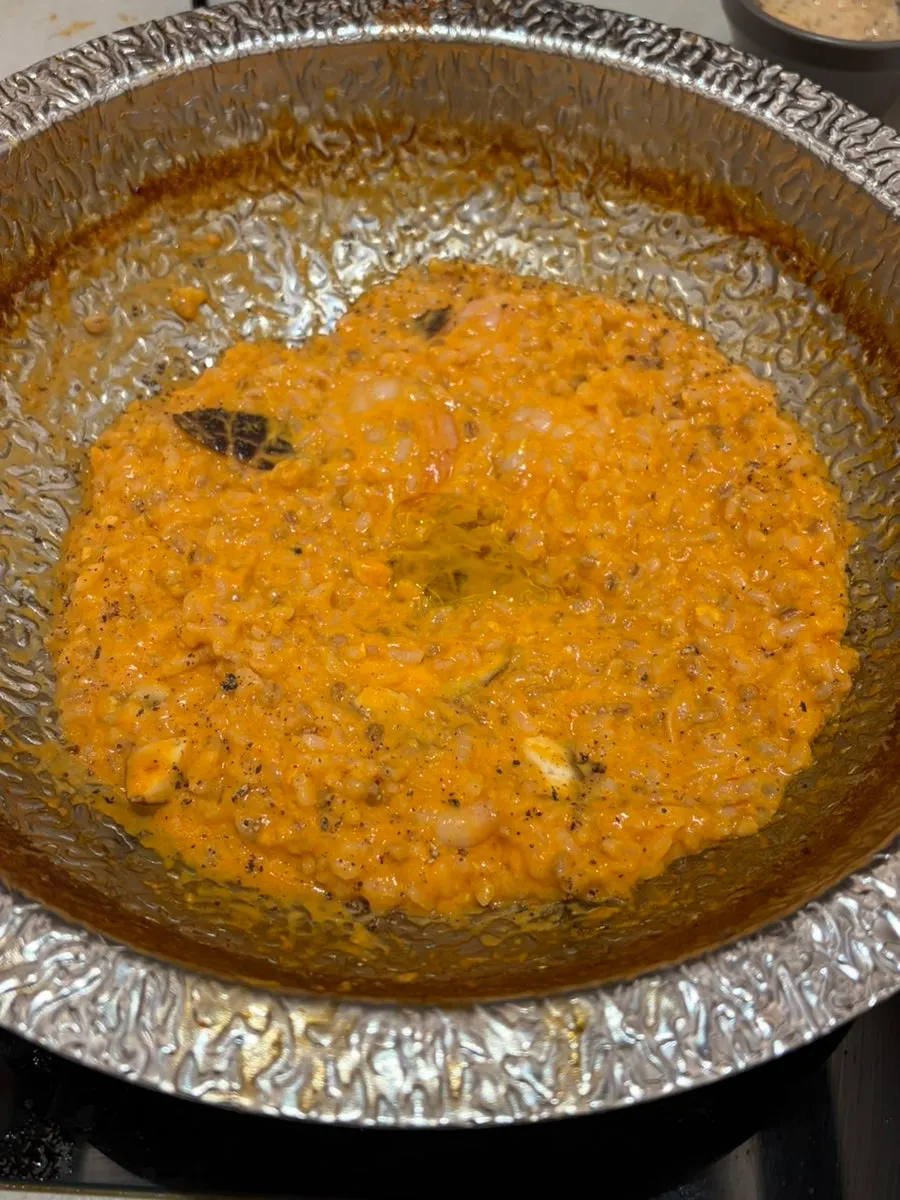 Staff member cooking the rose risotto finishing dish