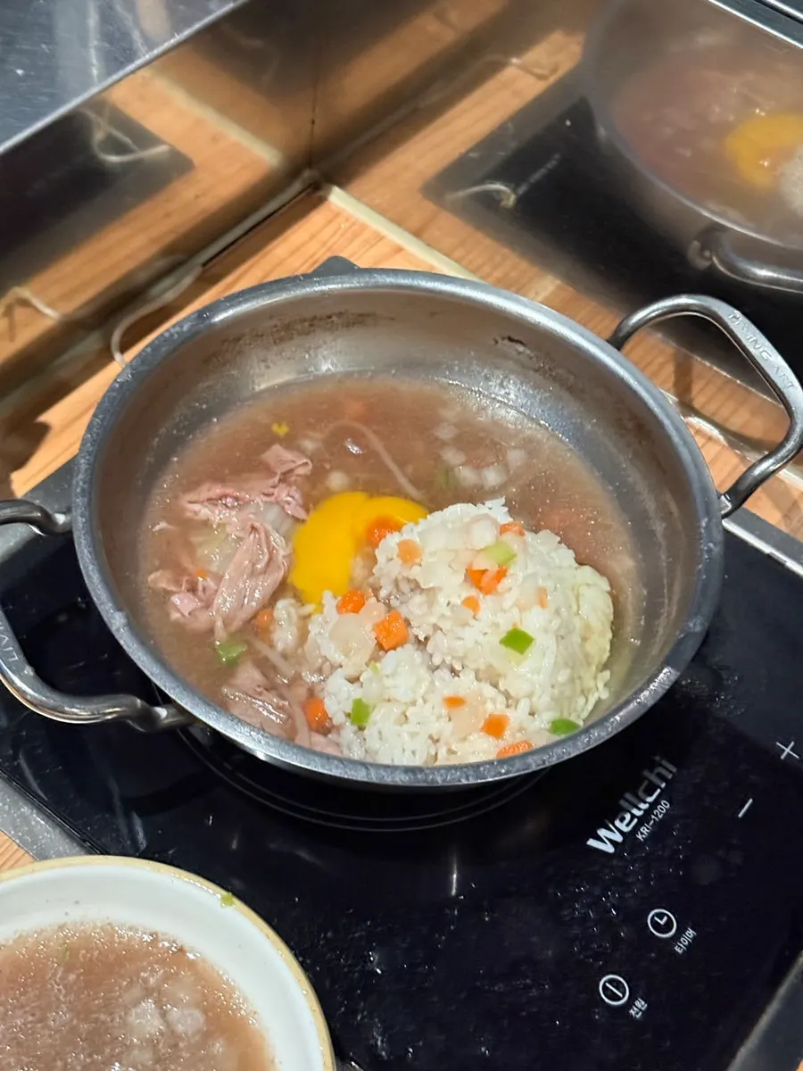 Self-made porridge being stir-fried with rice and egg in the leftover broth