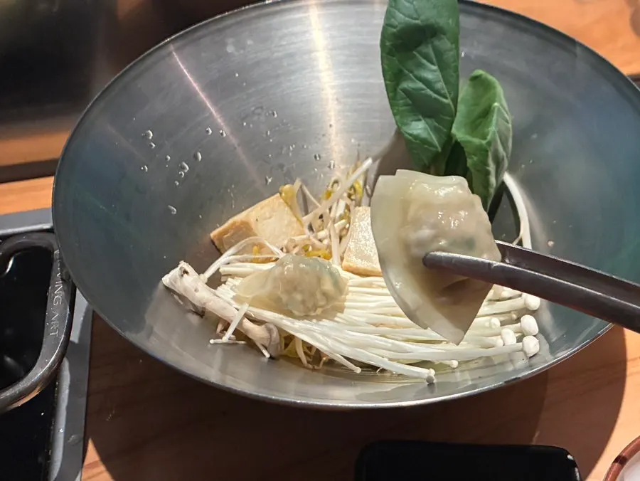 Cooked meat and meatballs lifted out of the pot