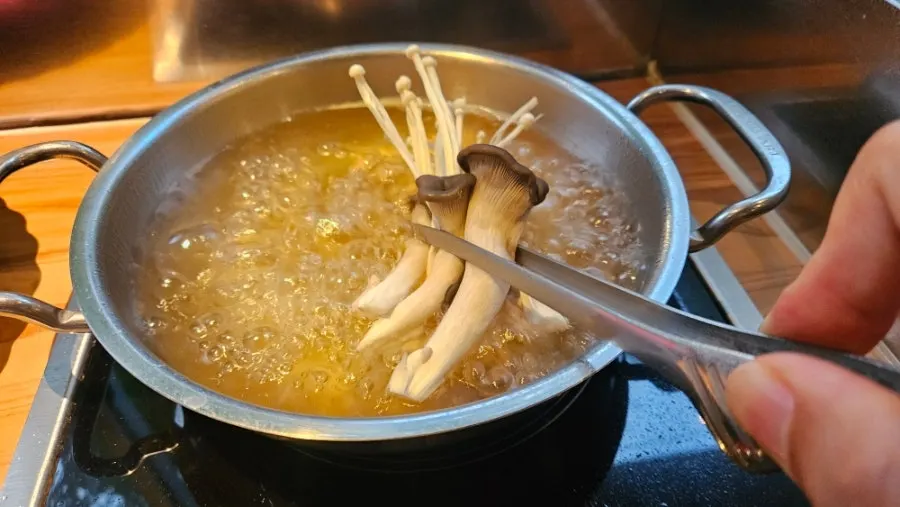 끓는 맑은탕 육수에 채소 넣는 모습