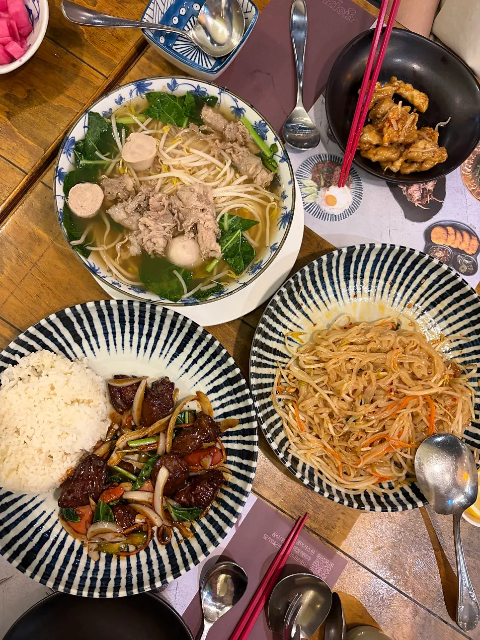 Table set with chicken pad thai, Thai rice noodle soup, and beef rice bowl