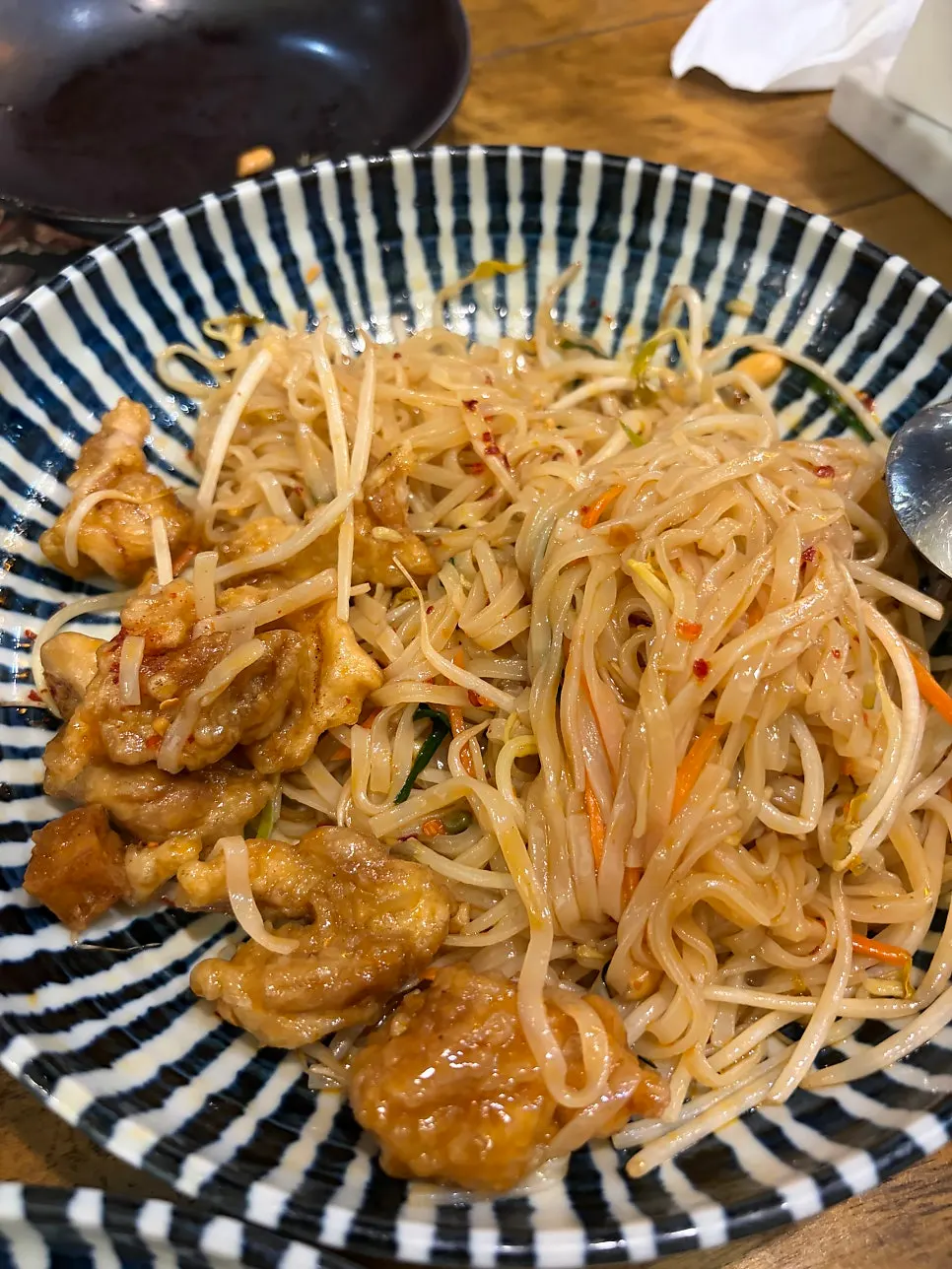 Pad thai topped with battered, fried chicken