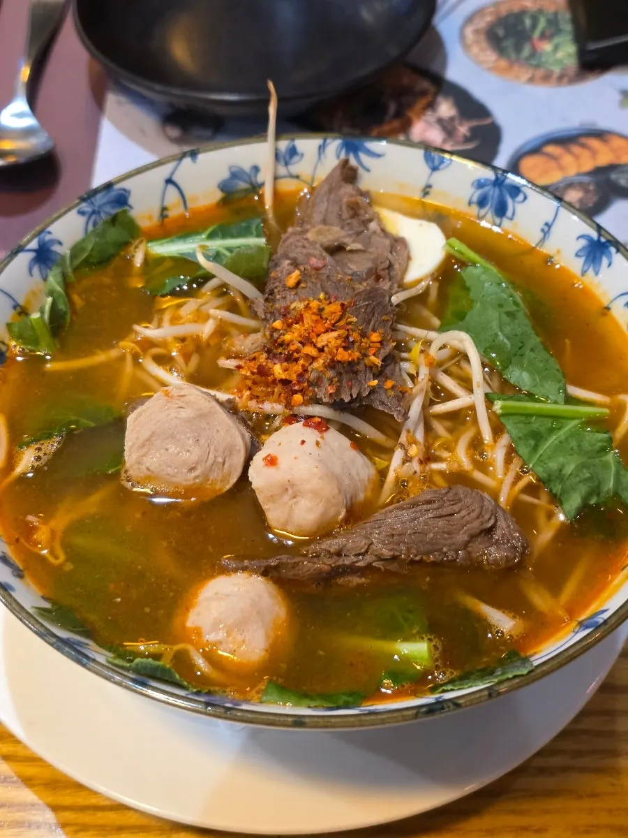 A bowl of tom yum rice noodle soup with broth