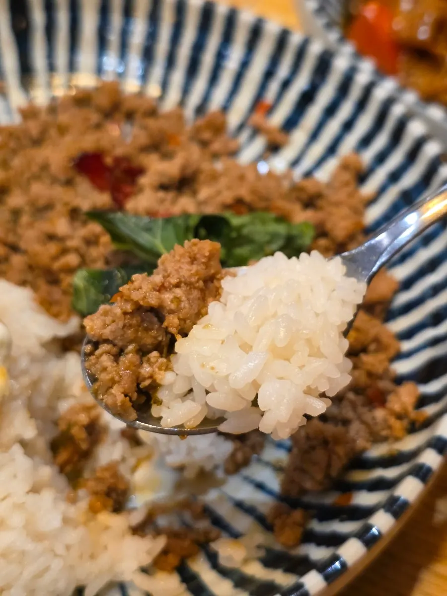 Scooping basil pork stir-fry together with rice