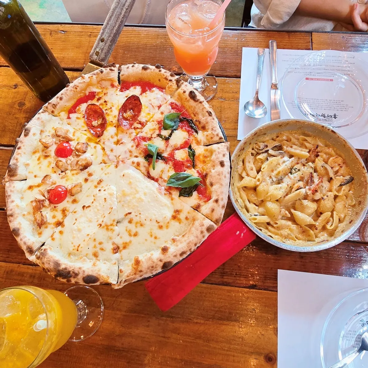 Wood-fired pizza and pasta table setting at Hongdae Hwadeok Pizza