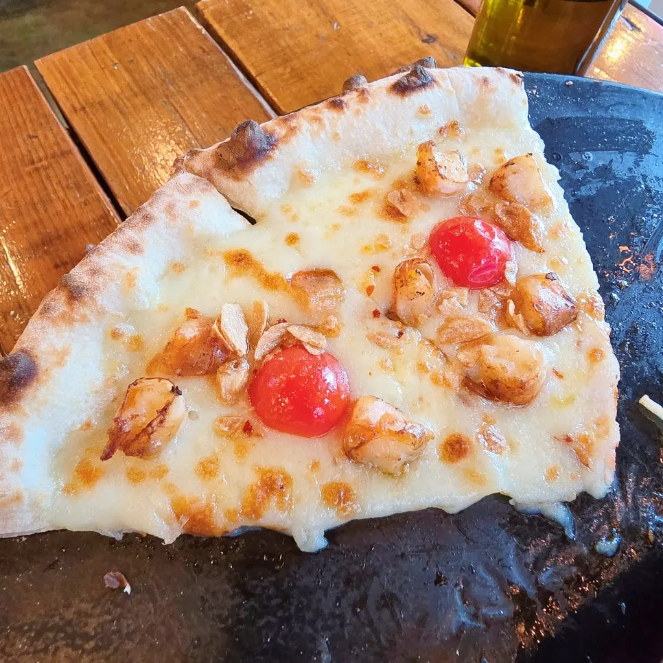 A slice of pizza from Hongdae Hwadeok Pizza with honey