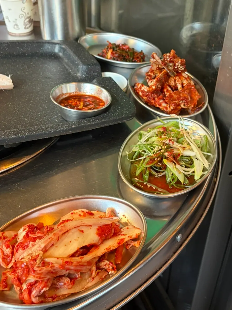 Table spread of basic banchan including kimchi and scallion kimchi
