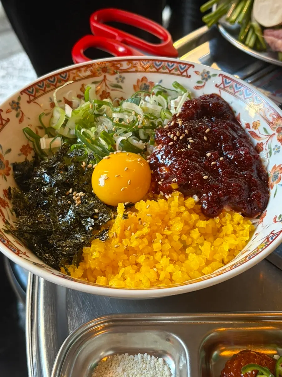 Spicy crab rice topped with raw egg, seaweed, and scallion