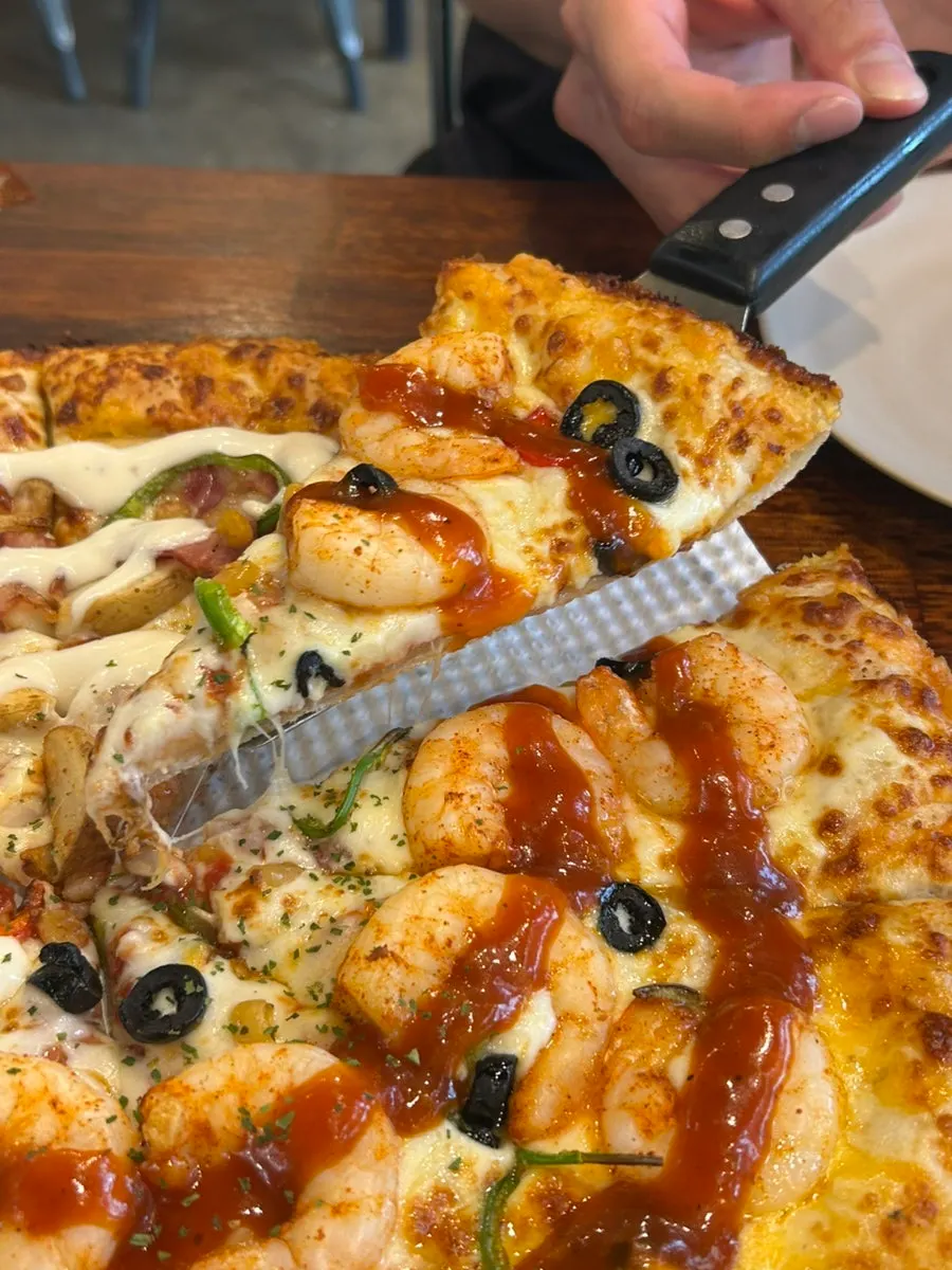 A pizza slice topped with plump shrimp