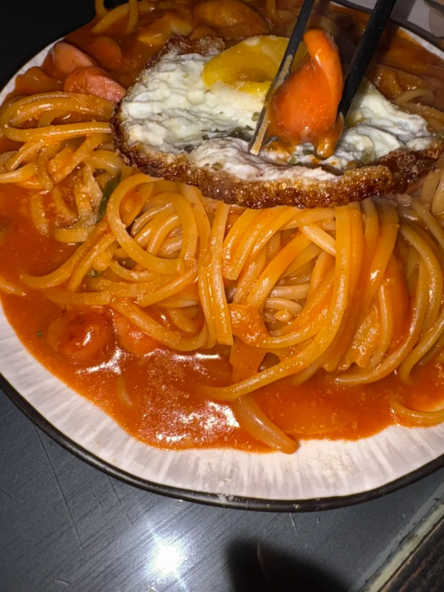 Napolitan pasta topped with sausage and a fried egg