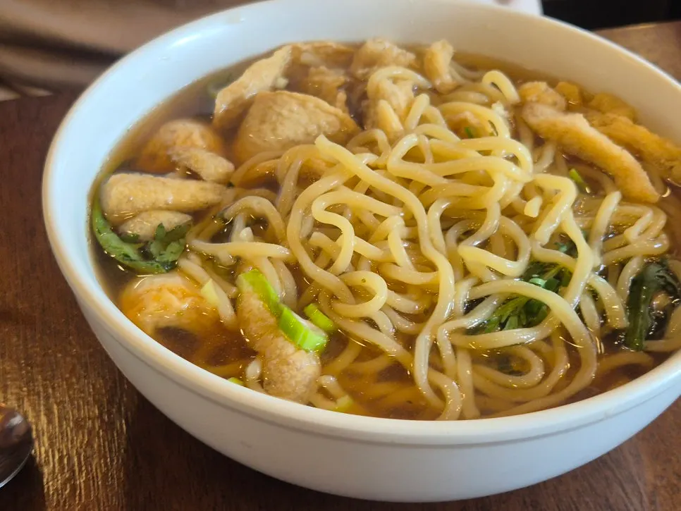 Picking up a piece of fish cake from the udon
