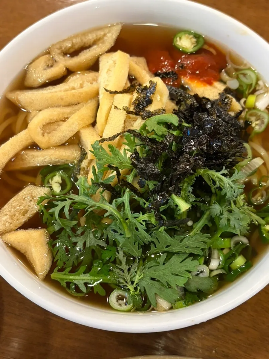 Spicy pepper udon topped with crown daisy and fried tofu