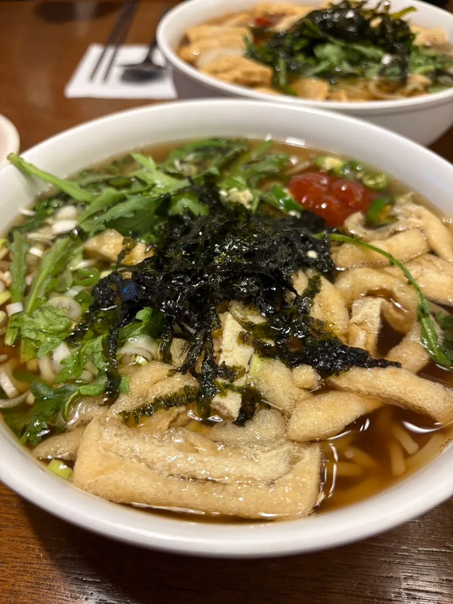 Fish cake udon topped with crown daisy and fried tofu