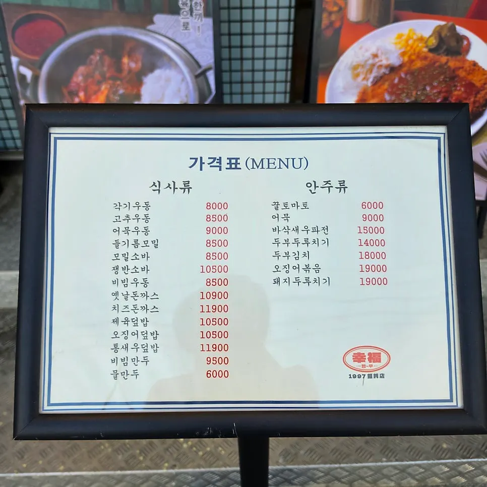 Menu board showing udon, soba, and pork cutlet dishes