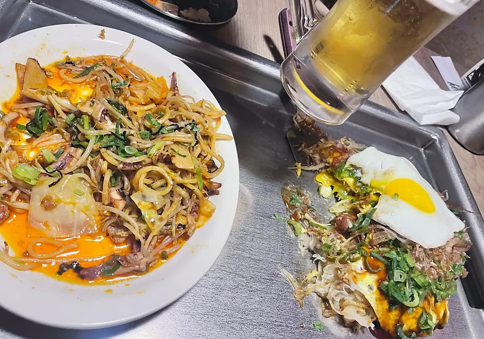 Table with okonomiyaki, yakisoba, and draft beer together