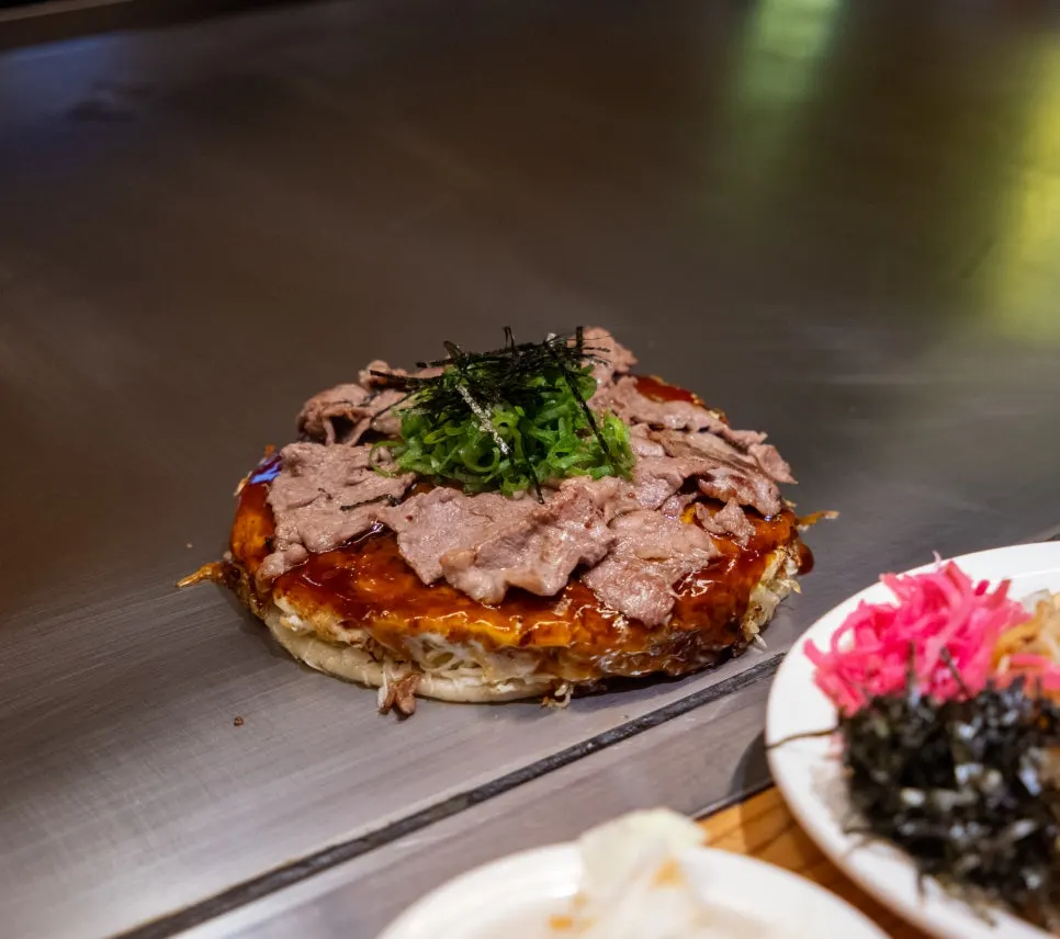 Yakisoba và bia tươi trên bàn trước chảo sắt